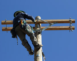 Linemen positioned on utility crossarms 
